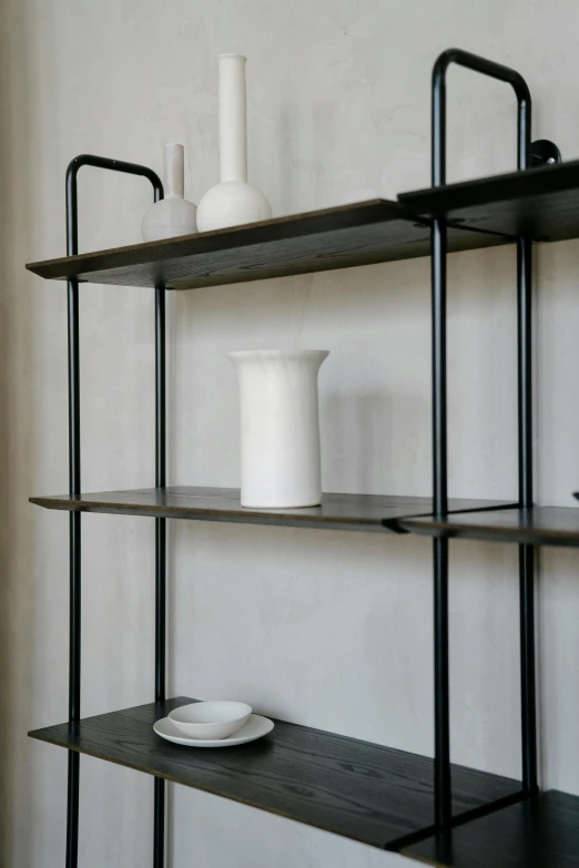 a black iron shelving unit with three shelves and one bowl