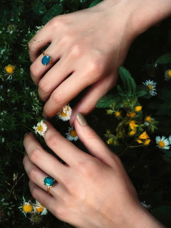 two hands holding different size rings and flowers