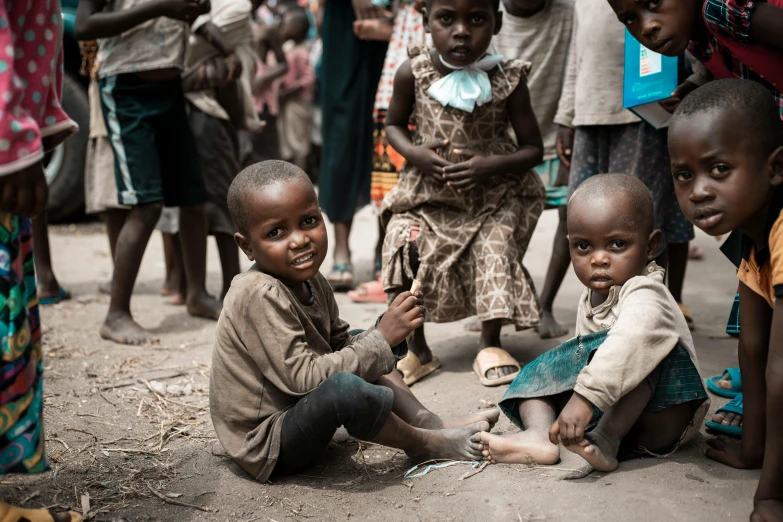 some young children and an adult siting on the ground