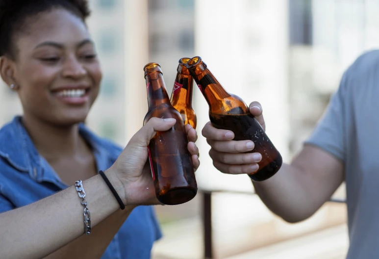 two people standing smiling and holding empty beer bottles