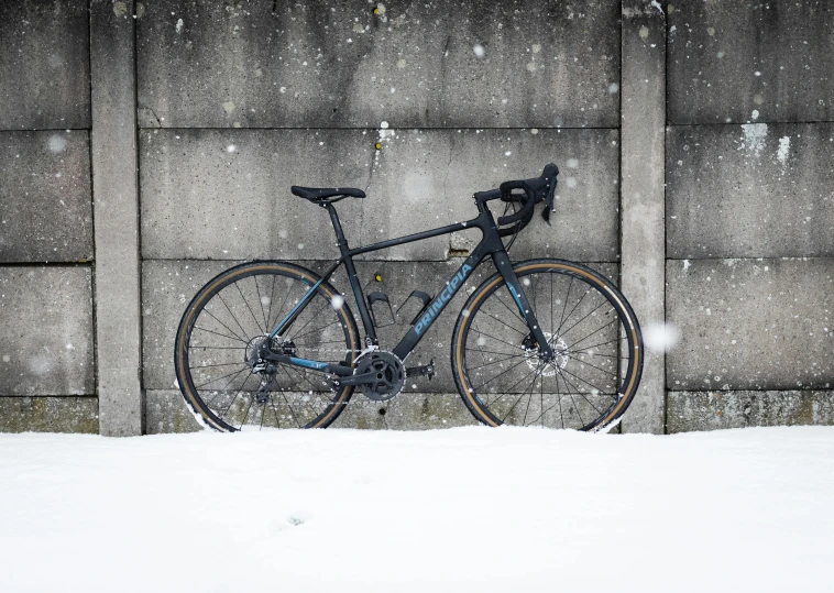 a bike leans against a wall on the snowy ground