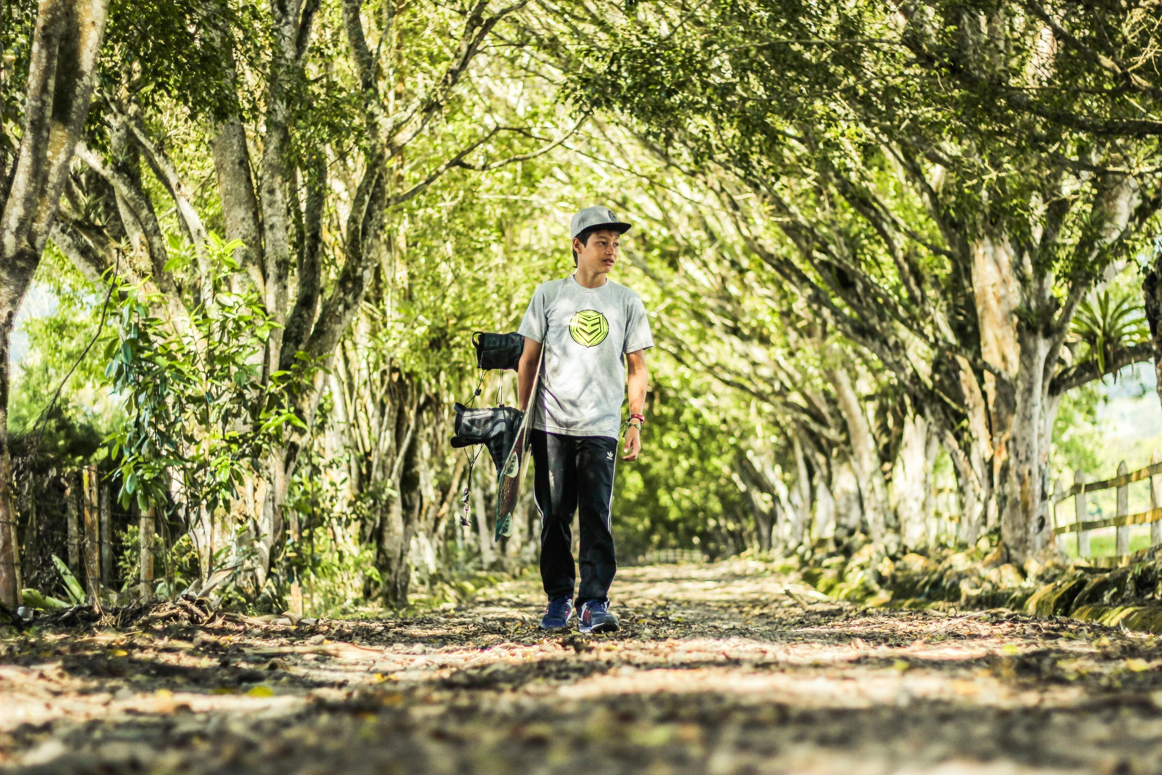 a man walking on a dirt path surrounded by trees