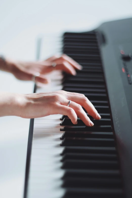 two hands on the piano playing it's keys