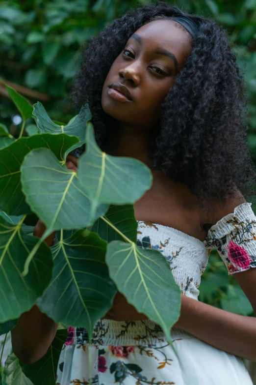 a young woman standing in front of a leaf