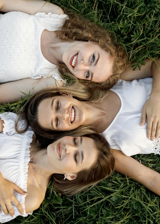 three women are laying down in the grass