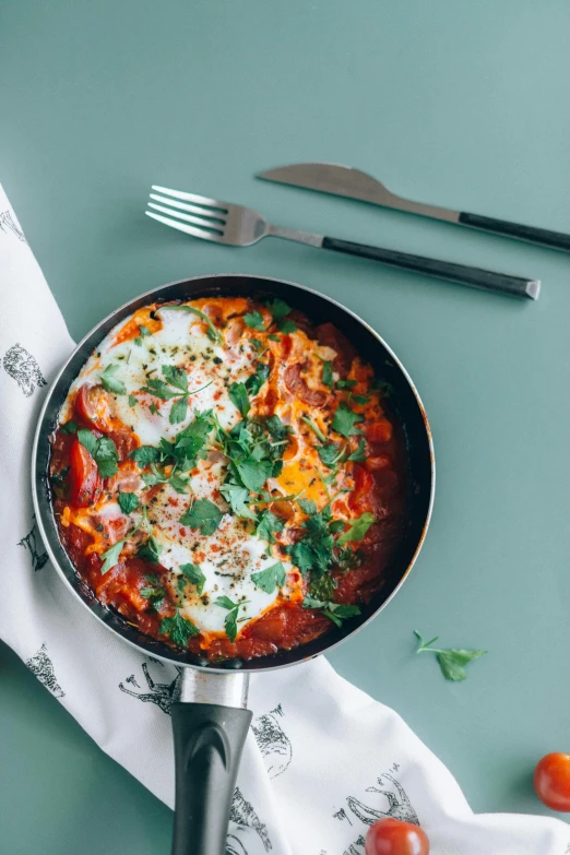 a wok of food with tomatoes and cheese on top