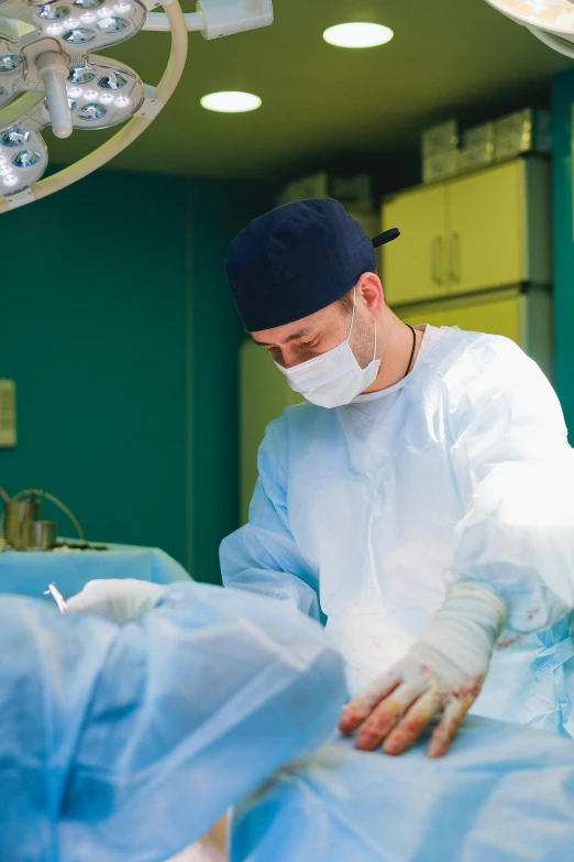 man in medical gown and headgear performs  on patient