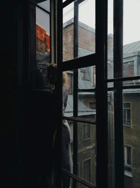 a woman is standing in a window looking out the windows