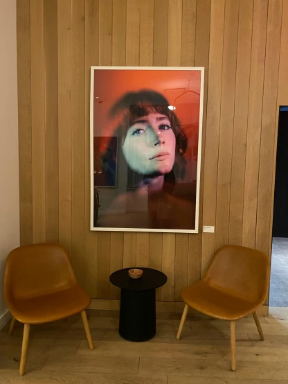 a large picture hangs above a wooden wall near two chairs
