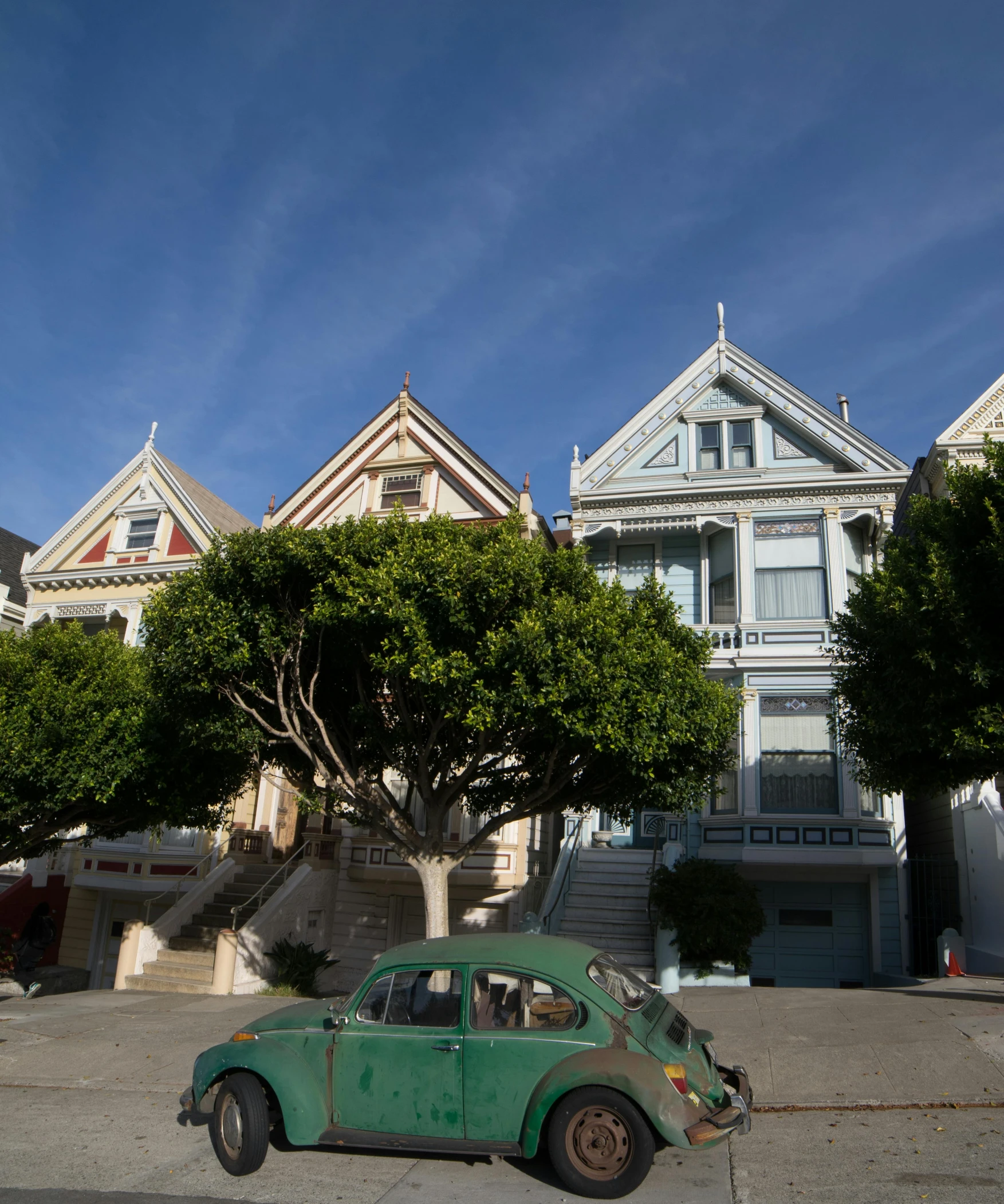 an old green car is parked in front of some houses