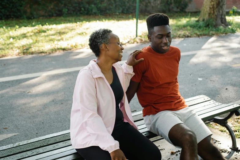 two black men are sitting on a wooden bench