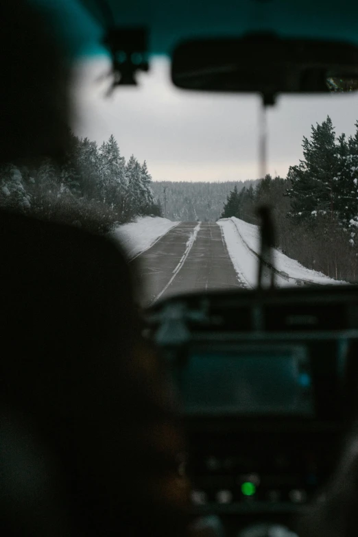 two people are driving down the road in the dark