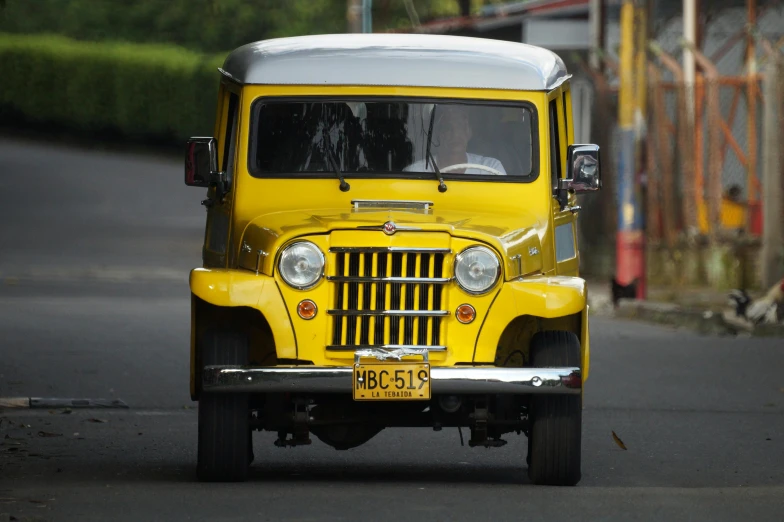 a yellow truck driving down the road next to a small shack