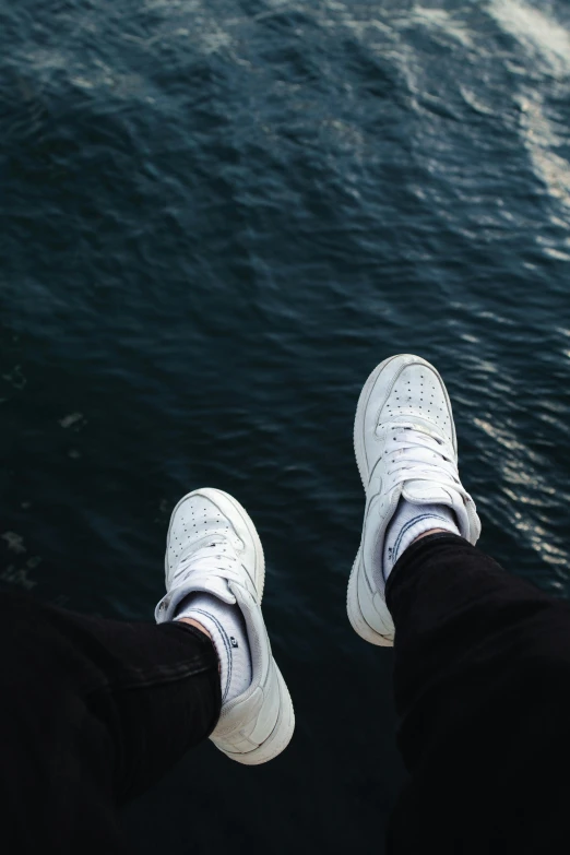 a couple standing in front of some water looking down at their feet