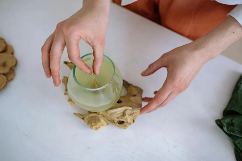 a person is squeezing tea into a glass