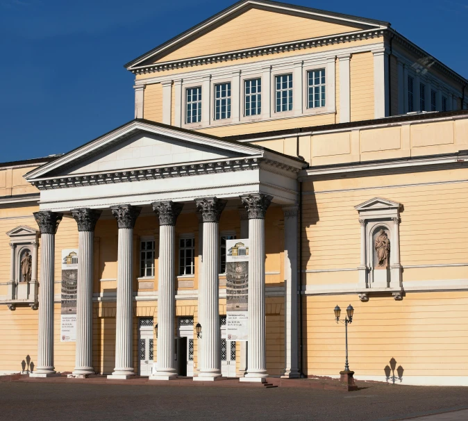 a tall yellow building with a small white statue sitting in front of it