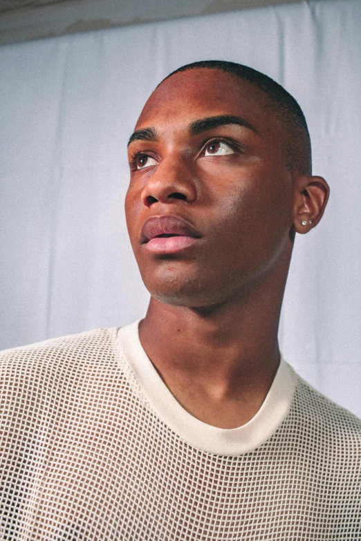 a black man in a white sweater looking away