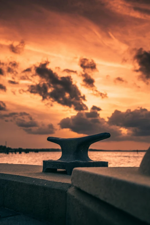 an iron object standing on a ledge near the ocean