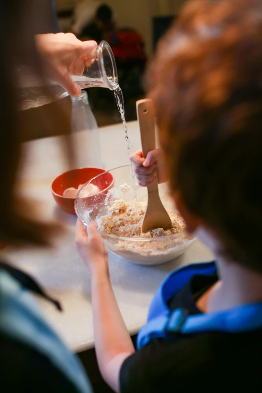 a woman pouring water over a bowl of food