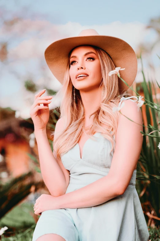 the blonde girl with the hat sitting on the grass