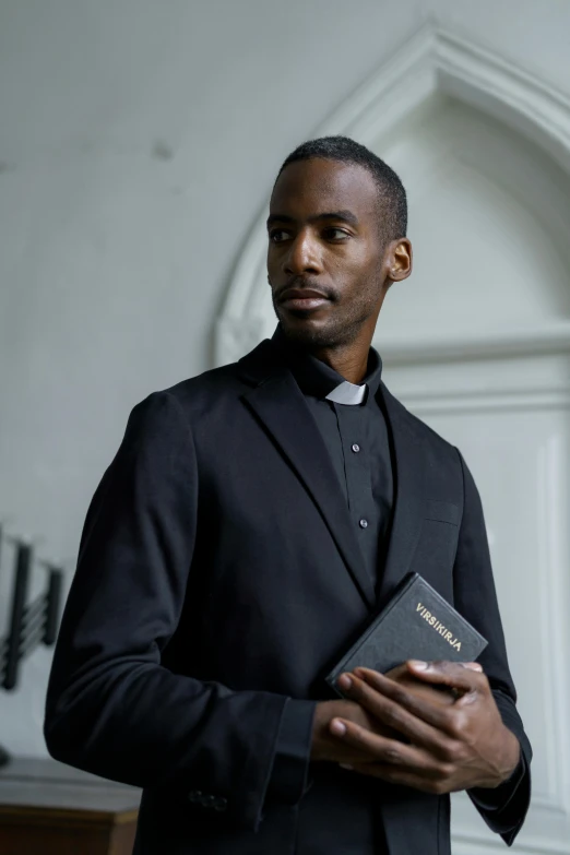 man in black coat holding an open bible