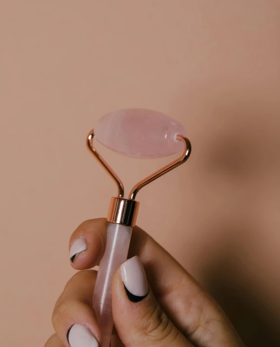 a hand holding an ope with black and pink nail polish