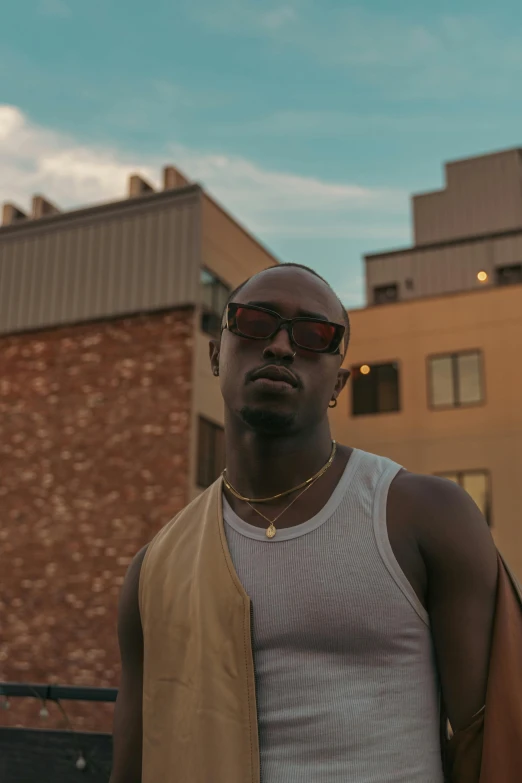 an african american man wearing sunglasses and standing in front of brick buildings