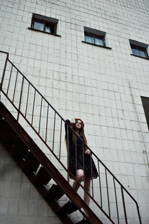 a beautiful young woman holding her hair down while standing on the stair case