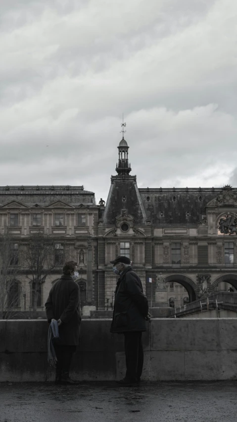 people sitting on benches in front of large stone building