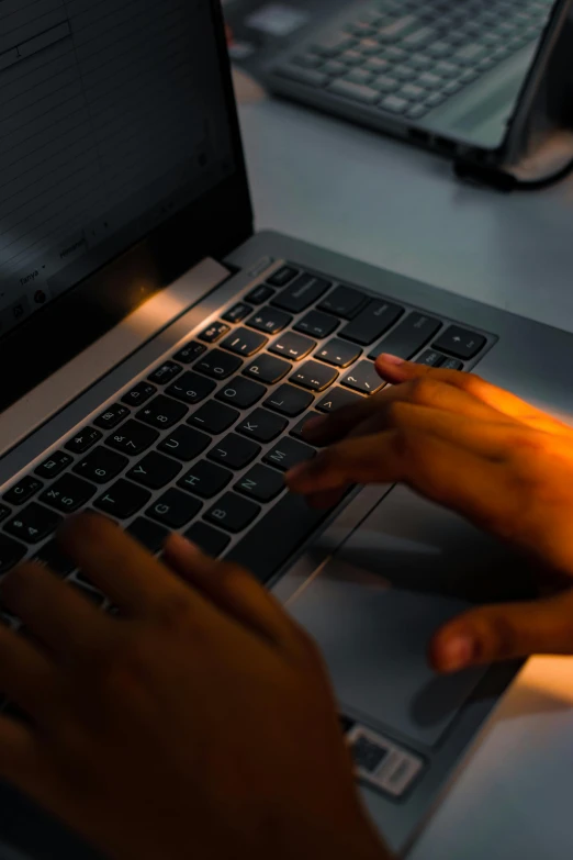 hands typing on laptop in dark room with laptop open