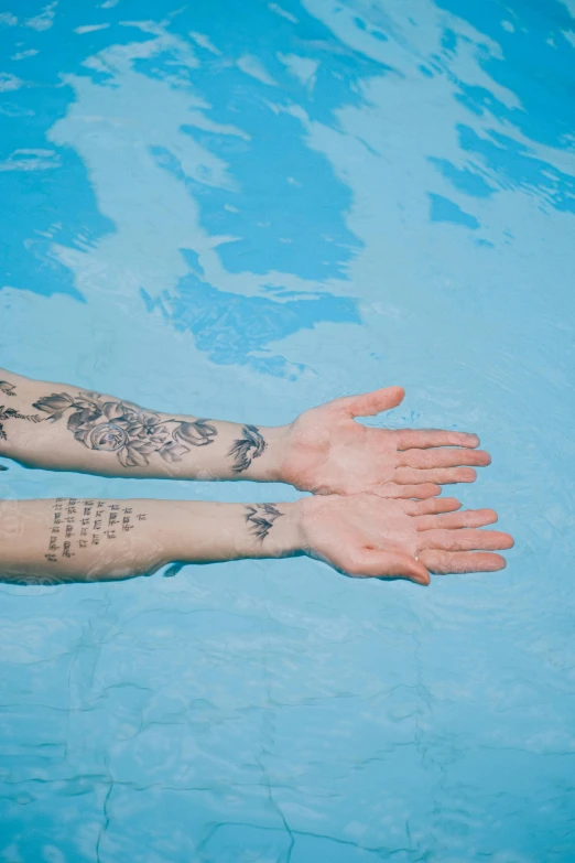 a person with arm tattoos and water in a pool