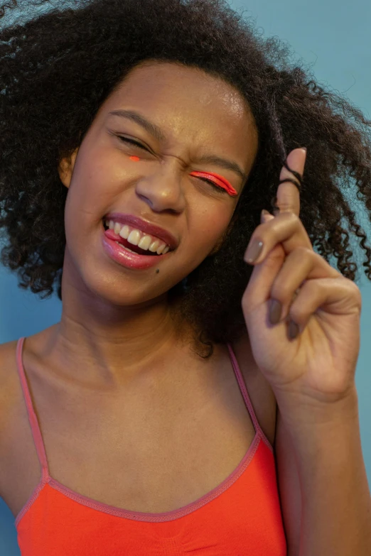 a woman wearing orange is smiling holding a cigarette