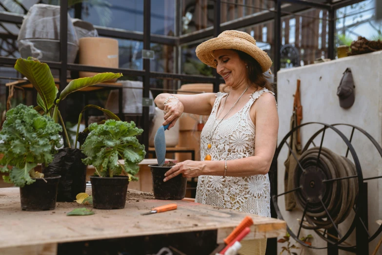 a woman wearing a straw hat chopping fruit on a board