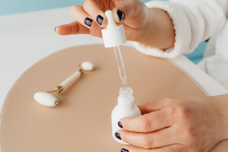 a person with black and white nails putting soing in a vial