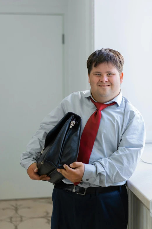 a man is posing for a po wearing his red tie and black briefcase