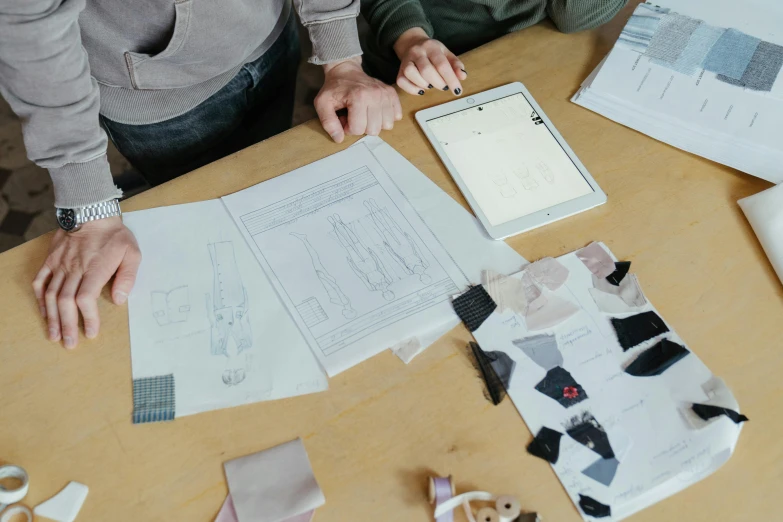 a couple of people sitting at a table with pieces of paper on top of it