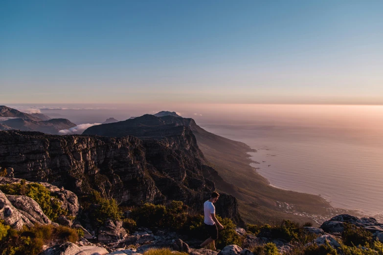 the man is standing on a mountain top looking at the mountains