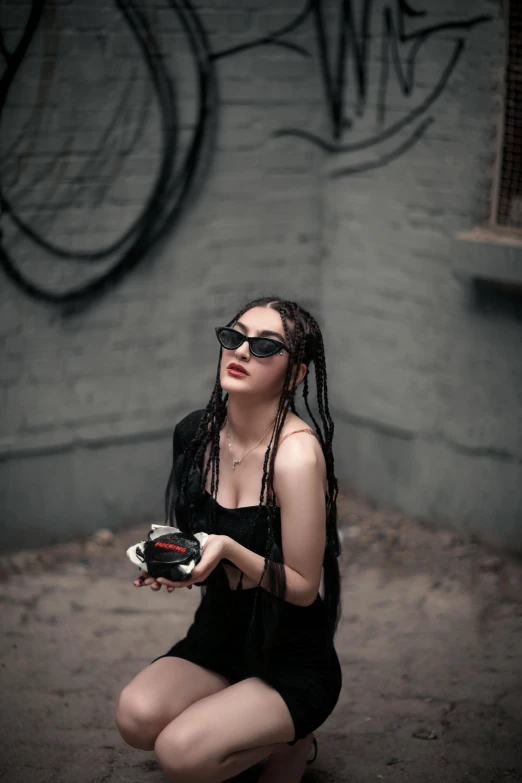 woman with sunglasses sitting in front of graffiti covered wall