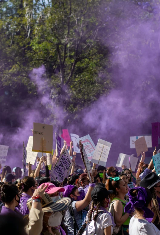 several people in the crowd hold up signs as a purple cloud is rolling in the background