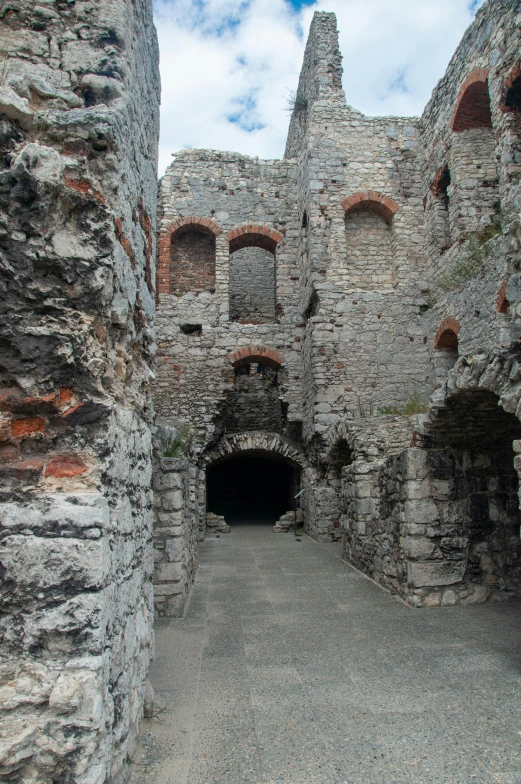 a path with many stone buildings and arches leading into it