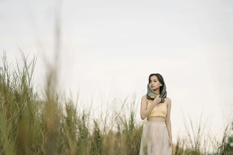 a woman is standing in tall grass on a sunny day