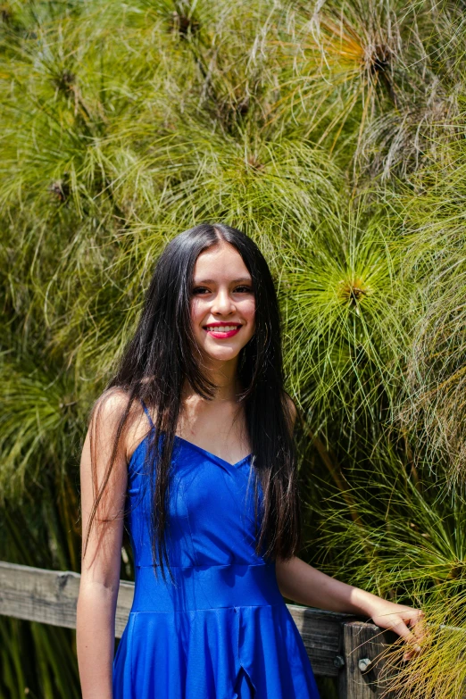 a girl wearing blue is standing by a tree