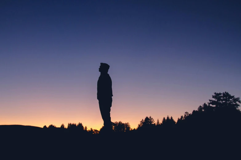 a person stands alone with their back to the camera, in silhouette