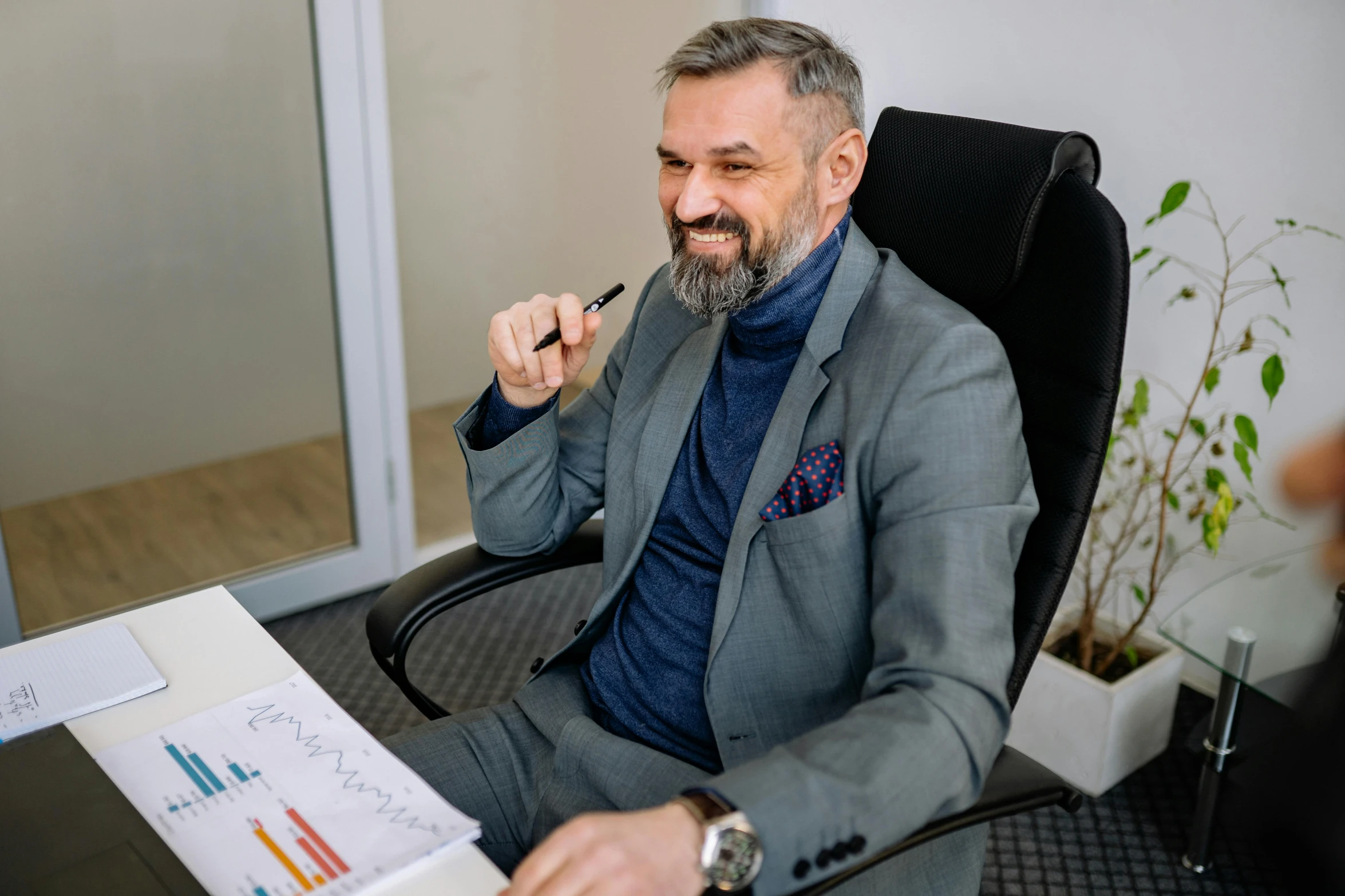 a business man sits on an office chair and points to a chart