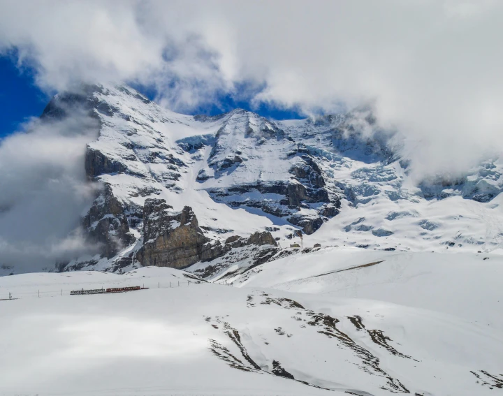 the mountains are covered in snow and clouds