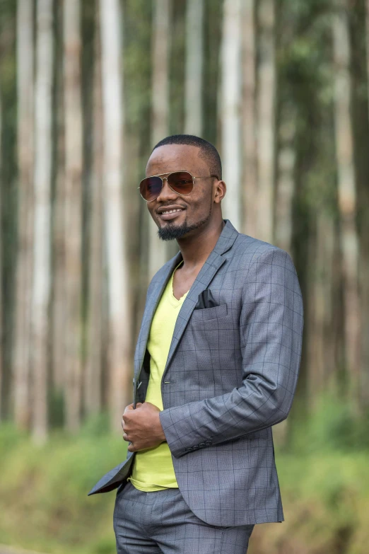 a black man is standing in a forest with sunglasses