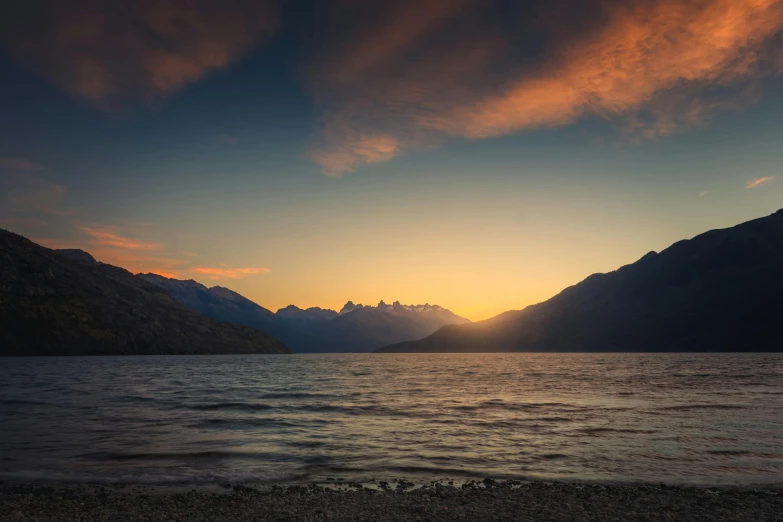 the sun is setting over some mountains on a lake