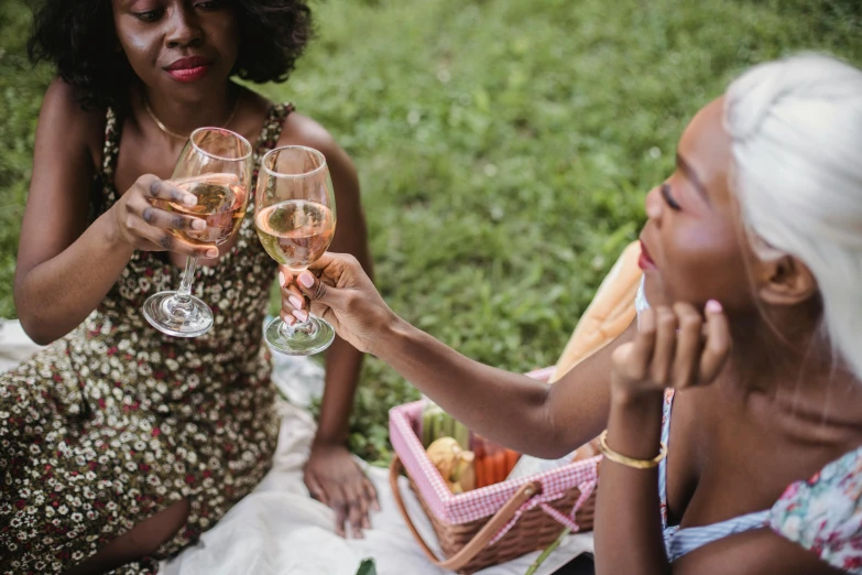 two women toast with pink wine glasses near other women