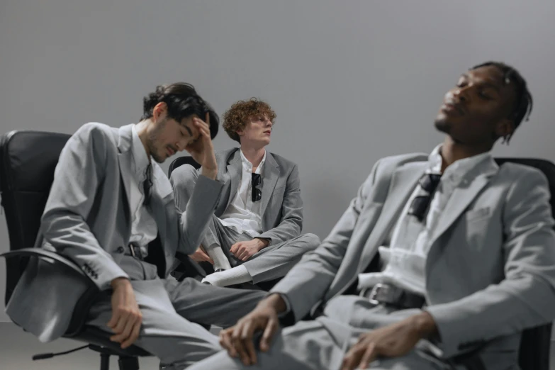 three men in business attire sitting on chairs