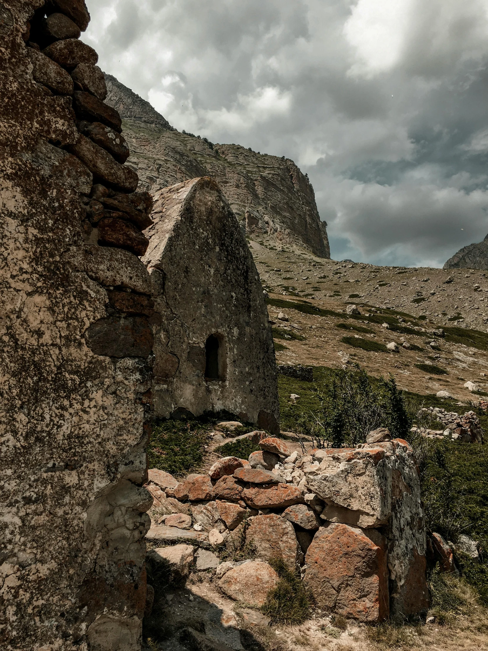 an old stone house made of bricks surrounded by rocky mountains